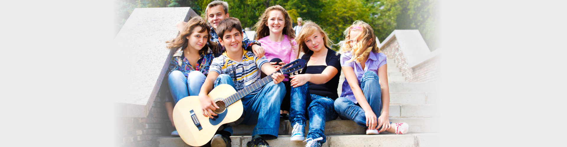 Group of friendly teens playing guitar